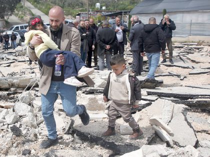 A Palestinian man carries his child amidst the rubble of a