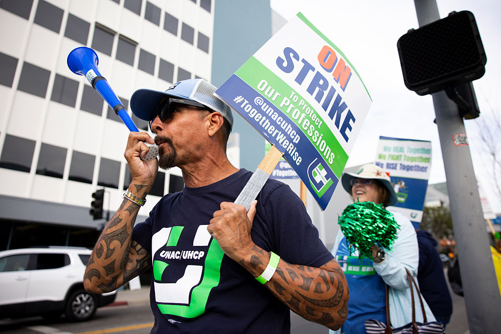 Rolando Escobar, right, a registered nurse, blows a horn during the strike in front of the Kaiser Permanente Los Angeles Medical Center on Monday, February 9, 2026, in Los Angeles, California.