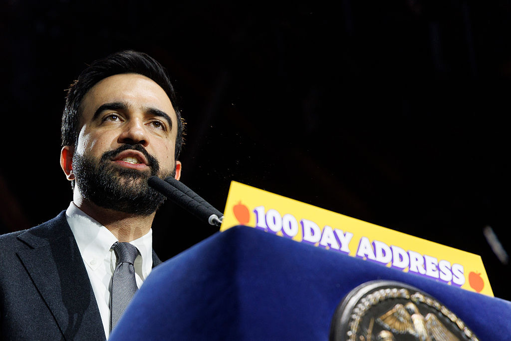 Mayor Zohran Mamdani speaking at a podium with a sign that says, "100 Day Address."