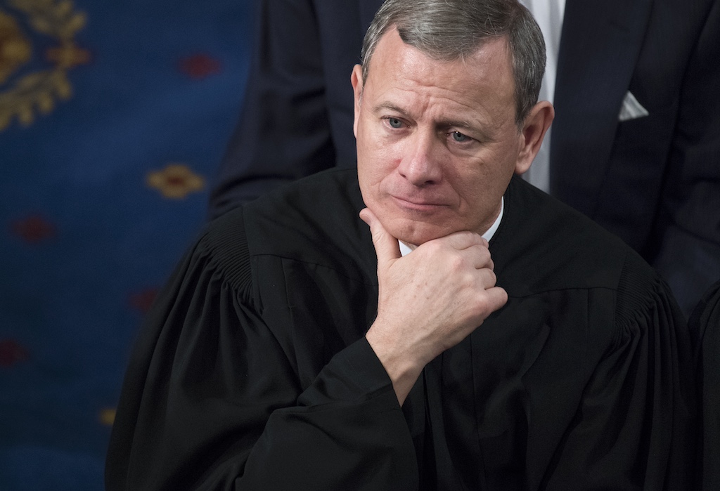Supreme Court Chief Justice John Roberts staring blankly while holding his hand to his chin.