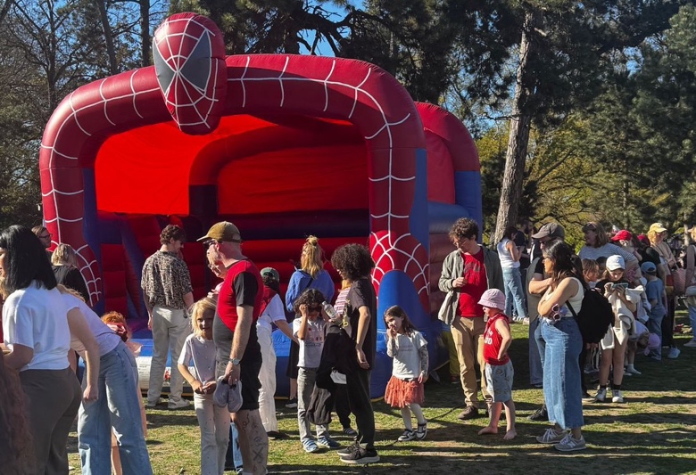 Families with young children gather around a Spider Man–themed bouncy castle.