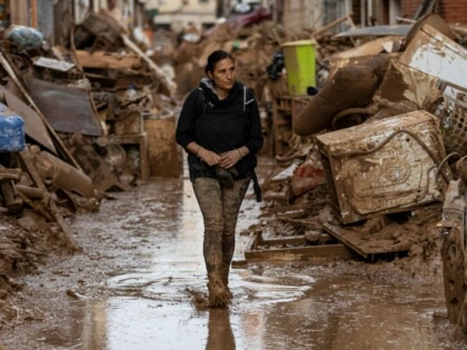A woman walks through flood damage.