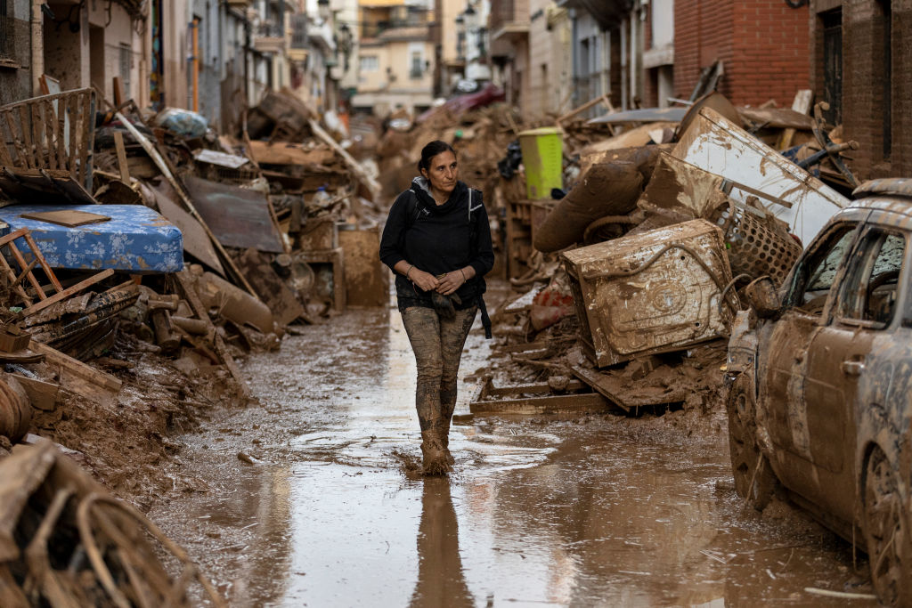 A woman walks through flood damage.