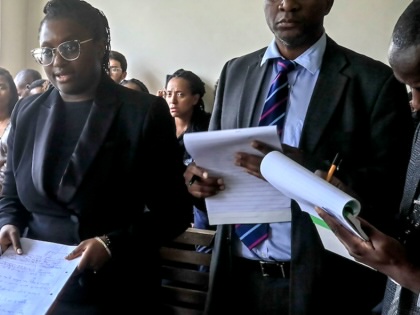 Three lawyers hold papers as one speaks.