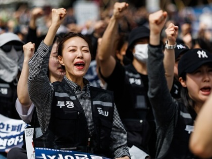 A worker holds her fist in the air surrounded by others. 
