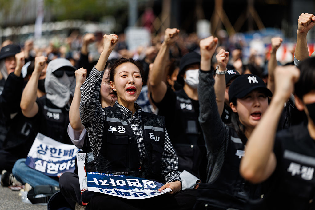 A worker holds her fist in the air surrounded by others. 
