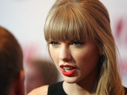 Taylor Swift speaking to a man with his back to the camera.