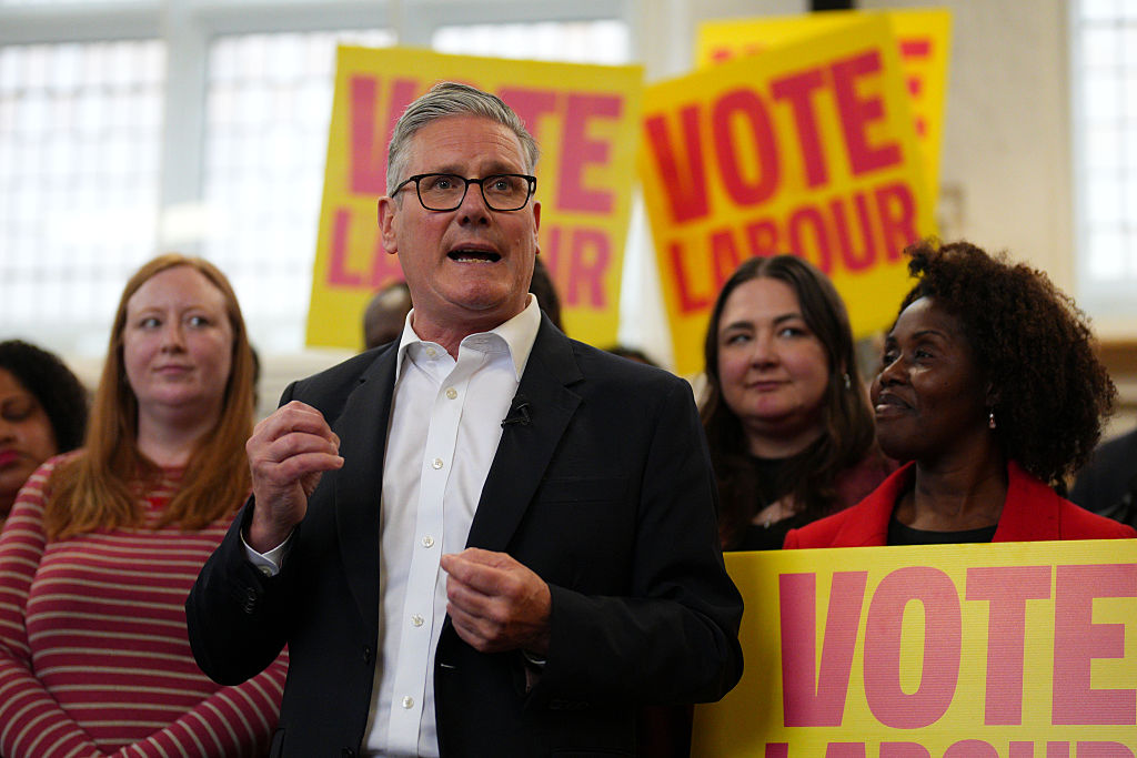 Keir Starmer gesturing while speaking to a crowd holding signs that say "Vote Labour."