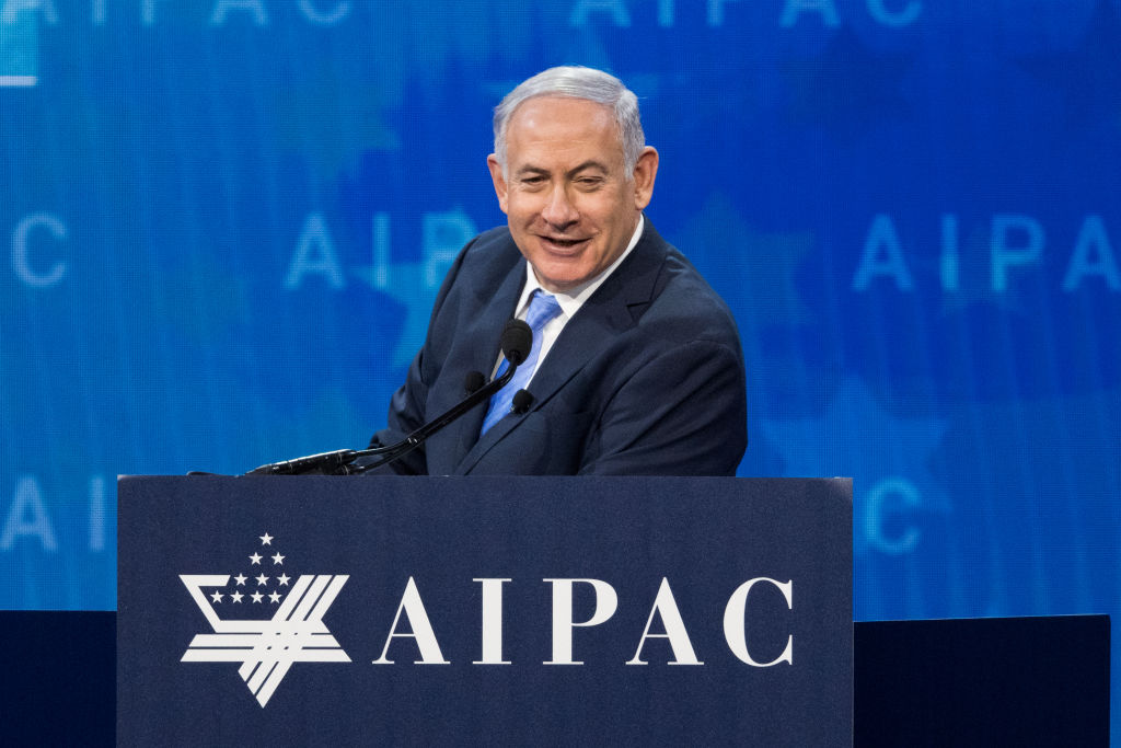 Benjamin Netanyahu stands at a podium that reads "AIPAC."