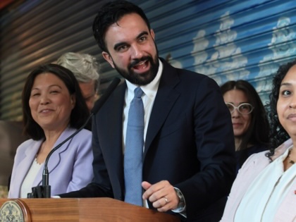 Zohran Mamdani speaking surrounded by members of his team.