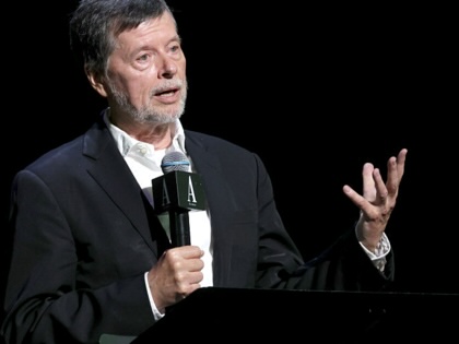 Ken Burns speaking in to a microphone while gesturing.