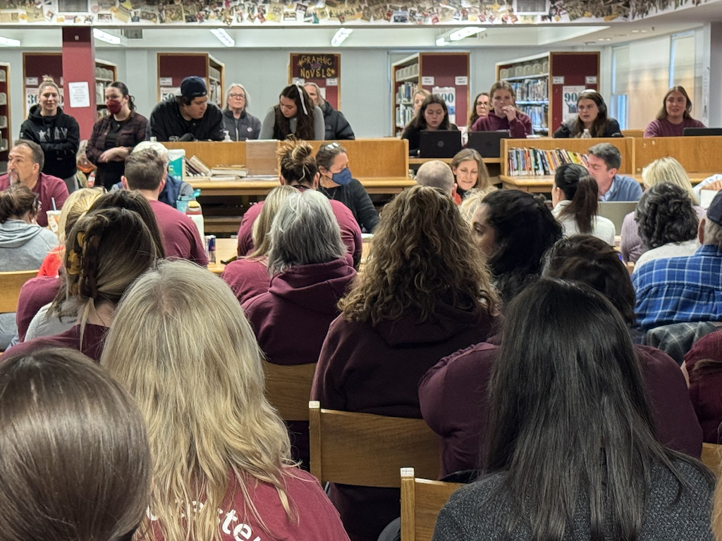 A group of people sitting in chairs and standing at a library.