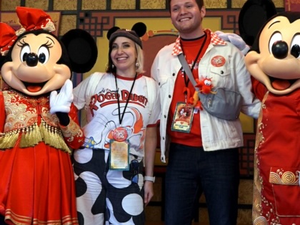 A couple poses with Mickey and Minnie Mouse.