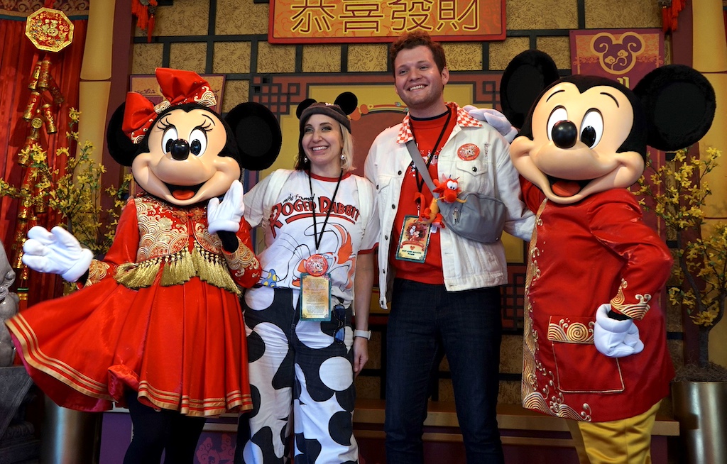 A couple poses with Mickey and Minnie Mouse.