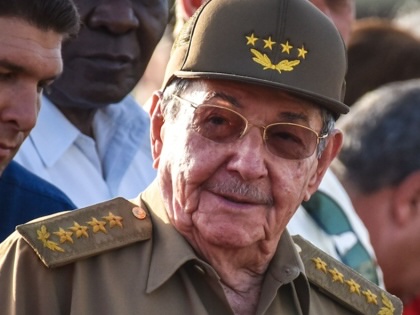 Raúl Castro wearing sunglasses and a green military hat with people surrounding him.
