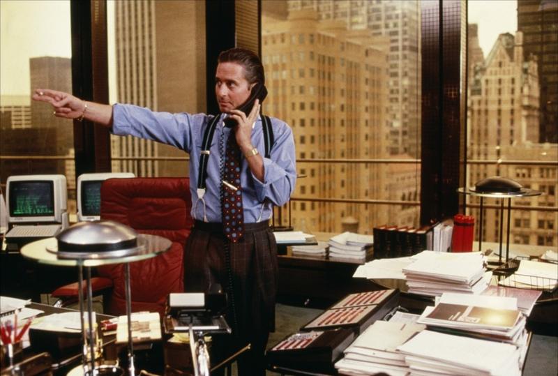 Still from Wall Street with Michael Douglas's character pointing while on the phone in an office.