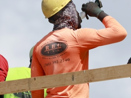 A man with a hard hat on drinking from a water bottle.