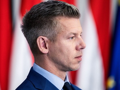 Peter Magyar's profile against a wall of Hungarian flags and one EU flag.