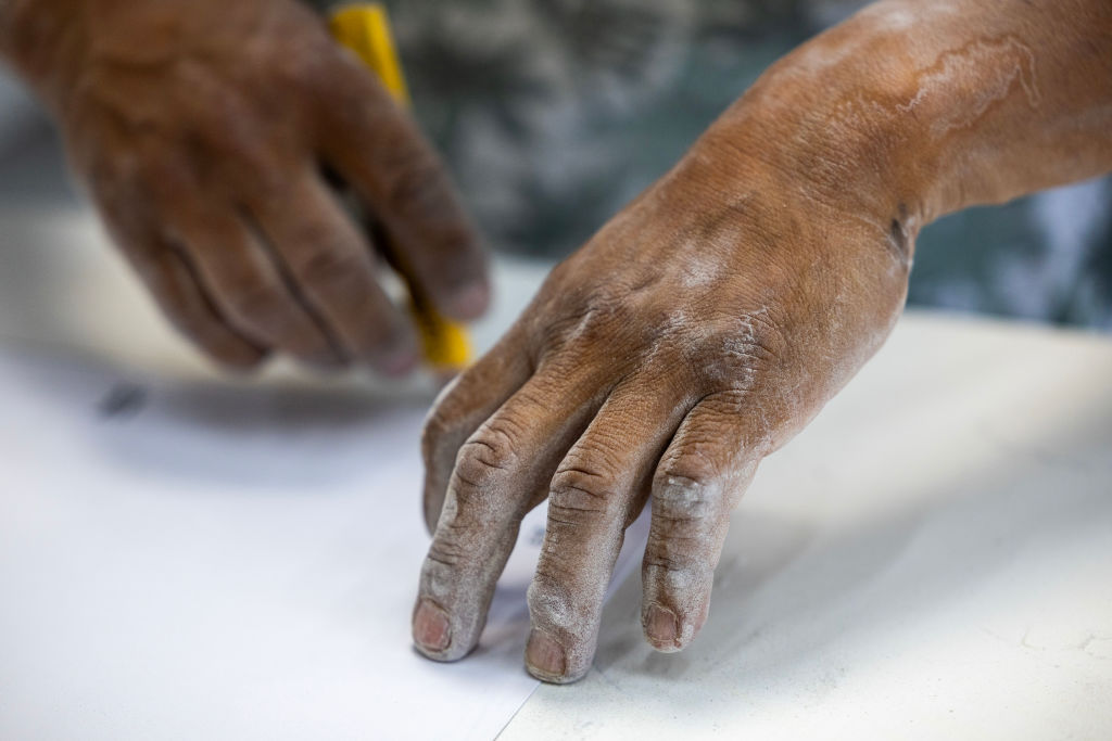 A stone countertop fabricator’s hands are covered in dust at a shop on Tuesday, October 31, 2023, in Sun Valley, California.