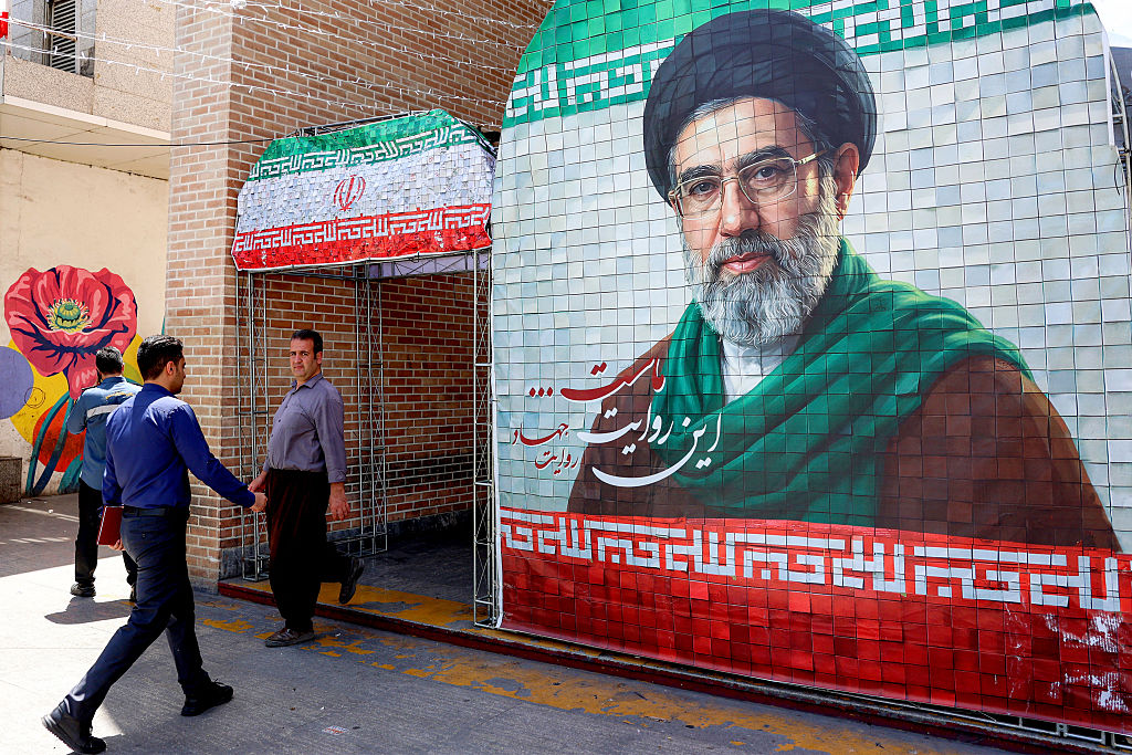 A man walks past a banner depicting Iran's current supreme leader Ayatollah Mojtaba Khamenei along a street Tehran on May 6, 2026.