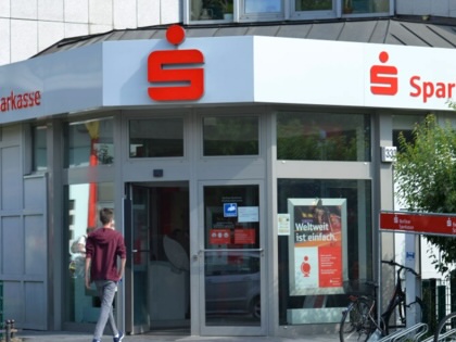A man walking into a Sparkasse bank building.