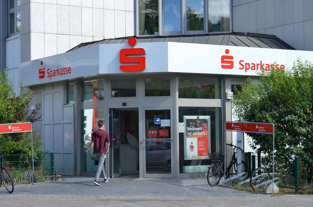 A man walking into a Sparkasse bank building.