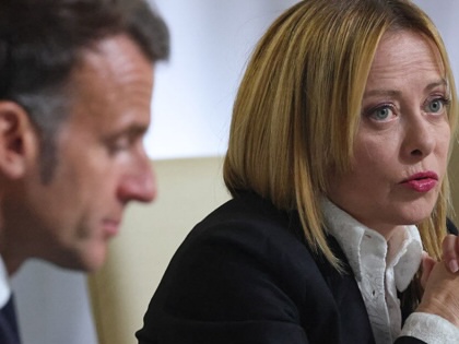 Giorgia Meloni speaking into a microphone with Emmanuel Macron in the foreground.