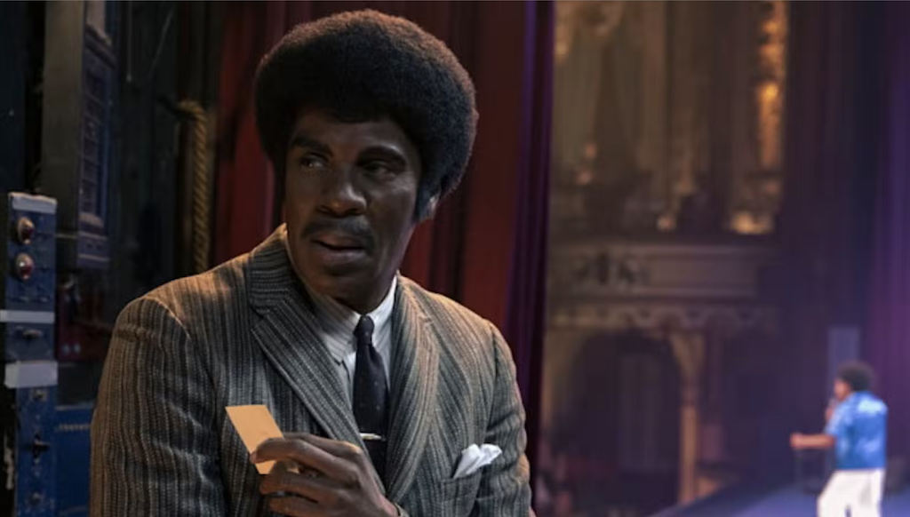 Actor Colman Domingo portrays Joe Jackson with a theater stage in the background.