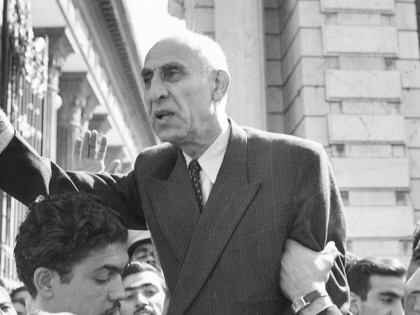 Mohammad Mosaddegh waving to a crowd while being lifted up by supporters.