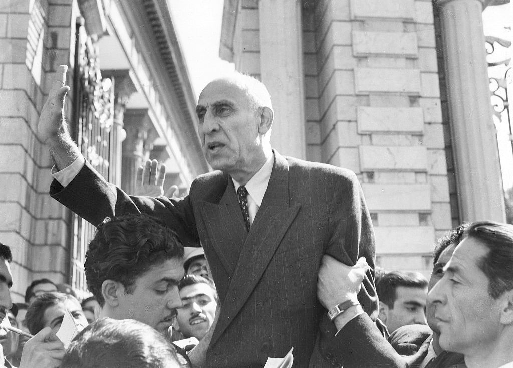 Mohammad Mosaddegh waving to a crowd while being lifted up by supporters.