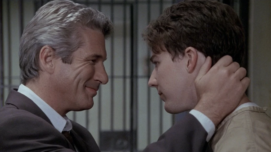 A still from Primal Fear where Richard Gere's characters is smiling at Edward Norton's character while grasping his neck.