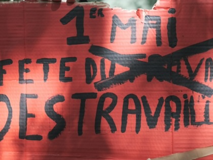 A red sign that reads "1st May fete du travail des traveileures," with an x over du travail.