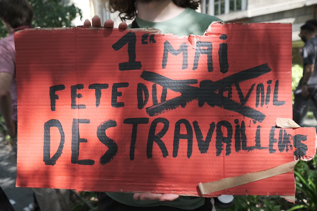 A red sign that reads "1st May fete du travail des traveileures," with an x over du travail.