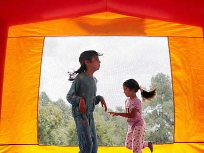 Two young girls jump in a bounce house.