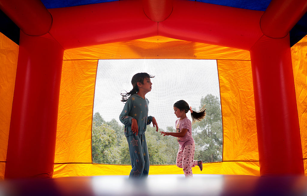 Two young girls jump in a bounce house.