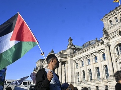 A man holds a Palestinian flag in front of Berlin's Reichstag government building.