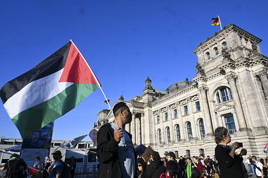 A man holds a Palestinian flag in front of Berlin's Reichstag government building.