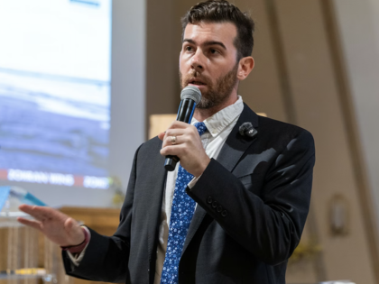 Oliver Larking speaking into a microphone while gesturing.