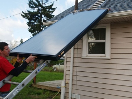 A man installs solar panels for a domestic hot water system in Salem, Oregon.