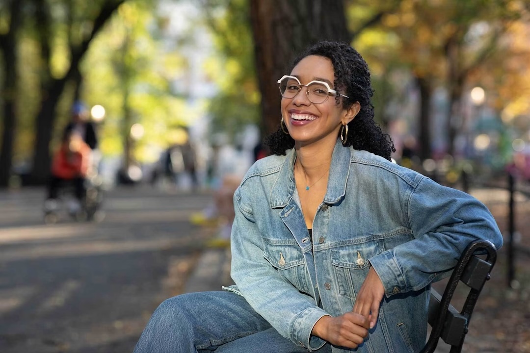 Darializa Avila Chevalier, sitting on a park bench and smiling.