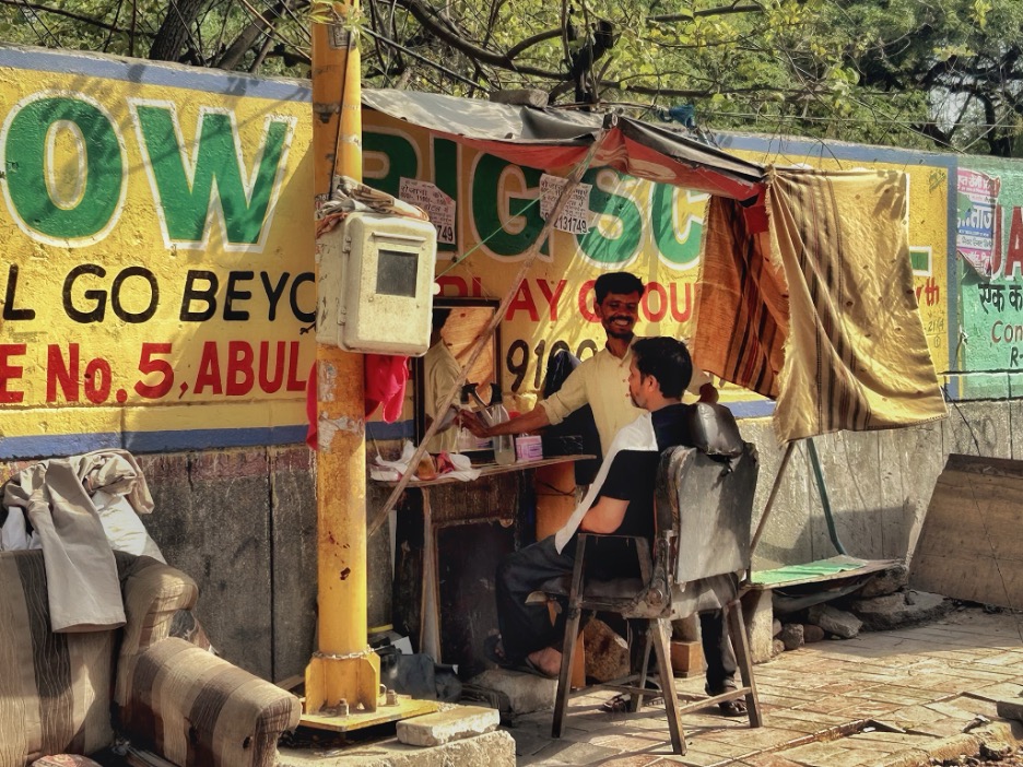 Migrant laborer Ashok Kumar, forty-two, runs a barber shop in India’s Zakir Nagar where temperatures are rising each day.