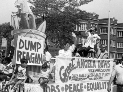Communist Party nominee for vice president Angela Davis waves to the crowd while riding in a float during the annual Bud Billiken parade, sponsored by the Chicago Defender, Chicago, Illinois, 1984. Activist and Senate candidate Ishmael Flory is visible on the right.