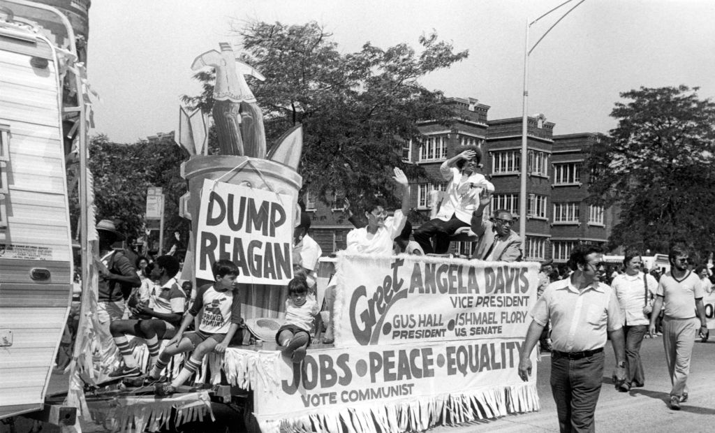 Communist Party nominee for vice president Angela Davis waves to the crowd while riding in a float during the annual Bud Billiken parade, sponsored by the Chicago Defender, Chicago, Illinois, 1984. Activist and Senate candidate Ishmael Flory is visible on the right.