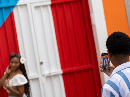 A man photographs a woman in front of a Puerto Rican flag mural in Old San Juan.