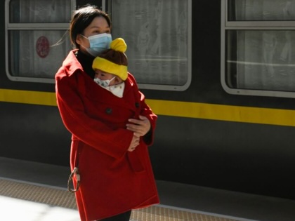 A migrant worker holding a child walks at a platform of Fuzhou Railway Station in China.