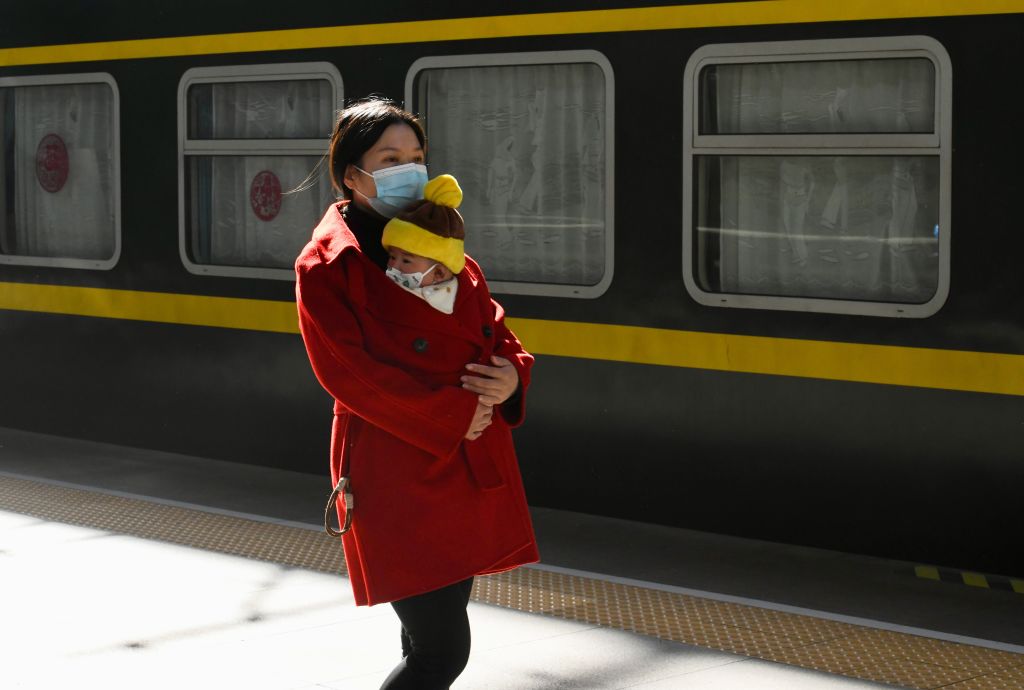 A migrant worker holding a child walks at a platform of Fuzhou Railway Station in China.