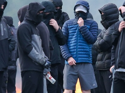 Masked youths block a road with burning debris in Belfast, Northern Ireland, on June 9, 2026.