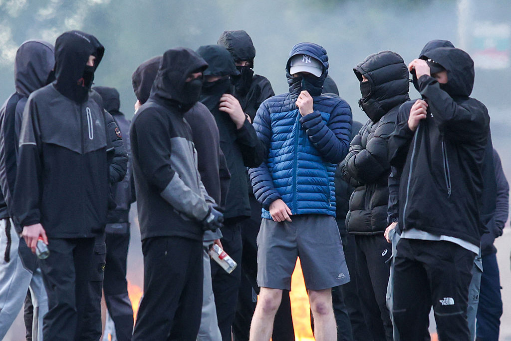 Masked youths block a road with burning debris in Belfast, Northern Ireland, on June 9, 2026.