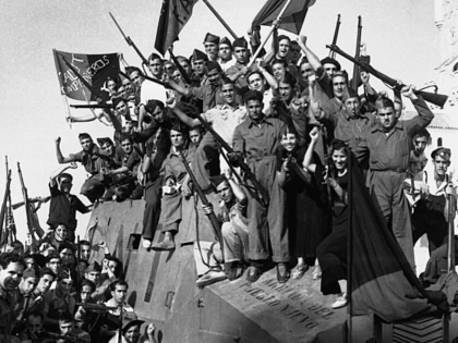 Anarchist militia members from the National Confederation of Labor wave their flags and rifles for the camera in Barcelona during the Spanish Civil War.
