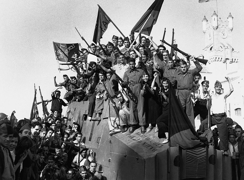 Anarchist militia members from the National Confederation of Labor wave their flags and rifles for the camera in Barcelona during the Spanish Civil War.